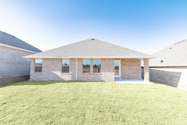 back of property with brick siding, a yard, a patio, and a shingled roof