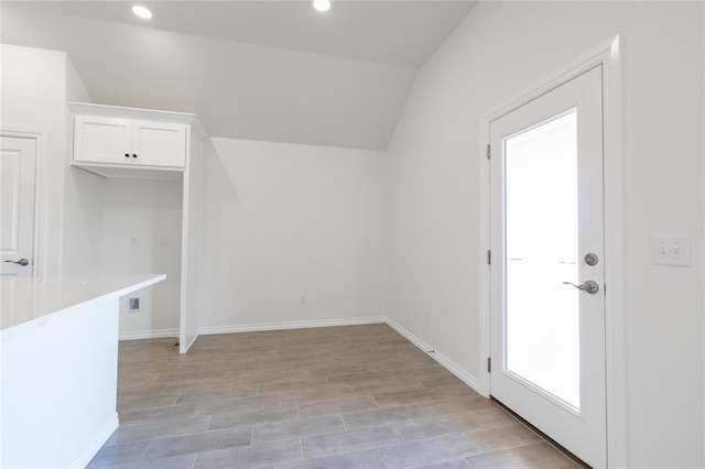 interior space featuring light wood-style flooring, baseboards, vaulted ceiling, and recessed lighting