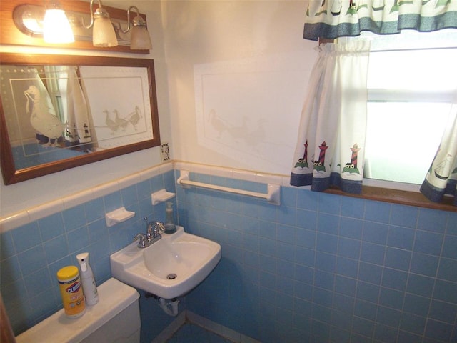 bathroom featuring toilet, sink, and tile walls