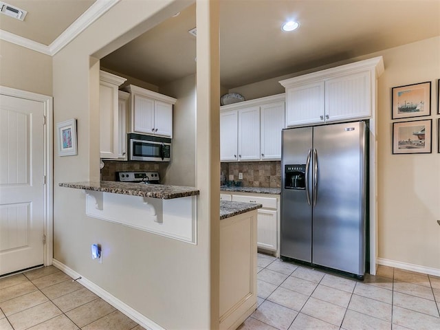 kitchen with backsplash, white cabinets, dark stone counters, and appliances with stainless steel finishes