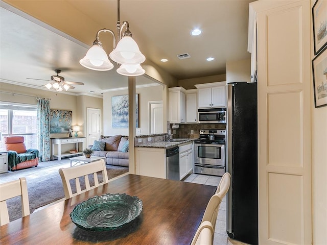 kitchen with dark stone counters, white cabinets, crown molding, decorative backsplash, and appliances with stainless steel finishes