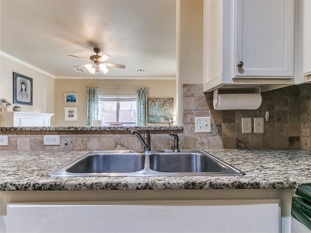 kitchen featuring white cabinets, backsplash, ornamental molding, and sink