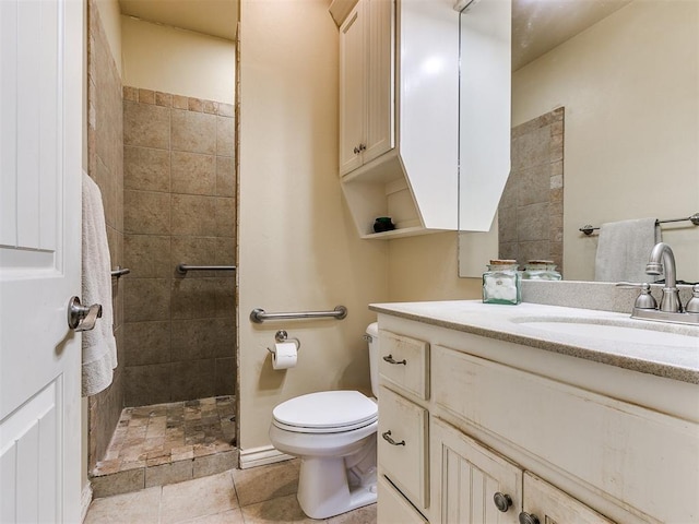 bathroom with tile patterned floors, toilet, a tile shower, and vanity