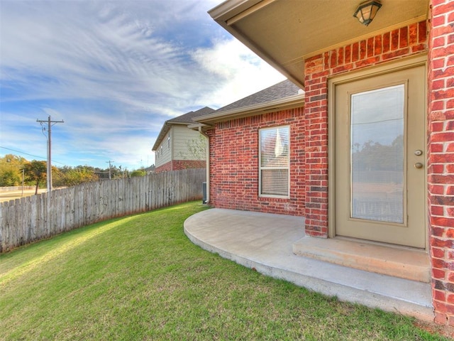 view of exterior entry with a patio and a lawn