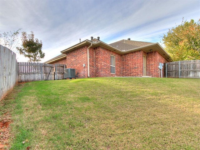 back of property with central air condition unit and a lawn