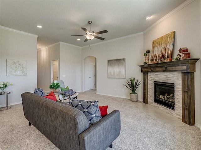 carpeted living room with a stone fireplace, ceiling fan, and ornamental molding