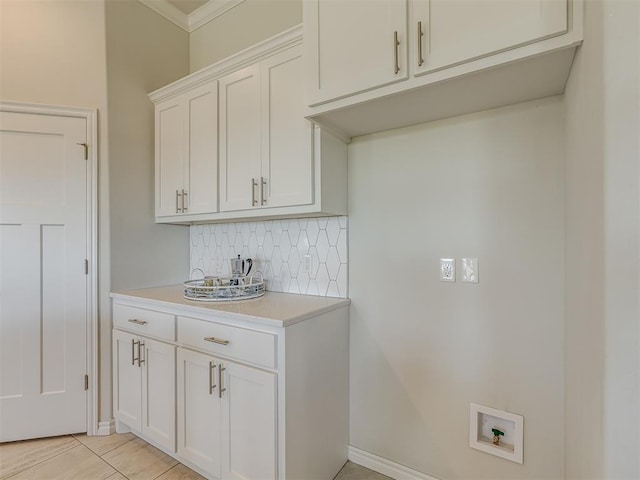 kitchen featuring decorative backsplash, light tile patterned floors, white cabinetry, and ornamental molding