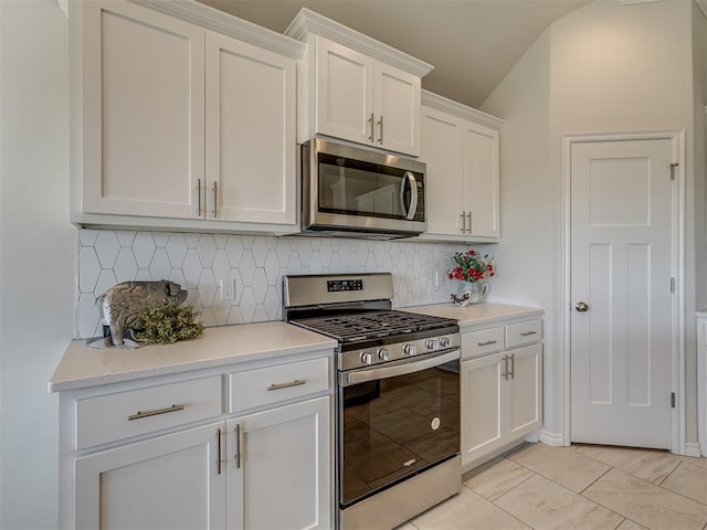 kitchen featuring tasteful backsplash, white cabinetry, vaulted ceiling, and appliances with stainless steel finishes