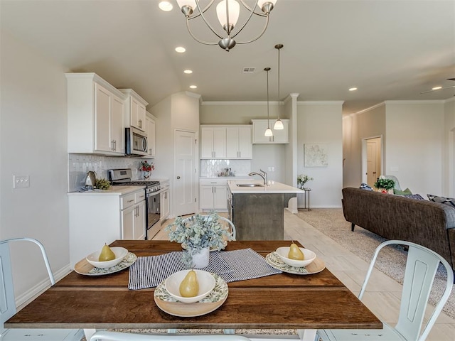 dining room featuring crown molding, sink, light tile patterned floors, and ceiling fan with notable chandelier