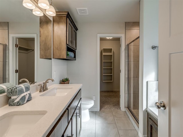 bathroom featuring tile patterned flooring, vanity, toilet, and a shower with shower door