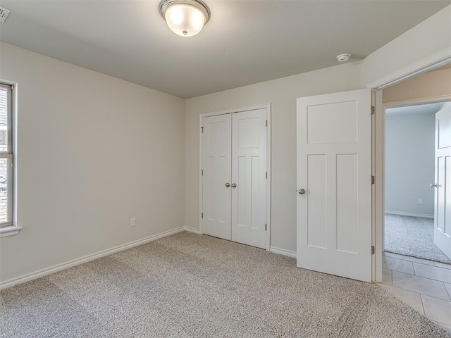 unfurnished bedroom with a closet and light colored carpet