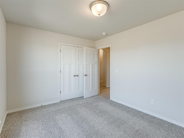 unfurnished bedroom featuring light colored carpet and a closet