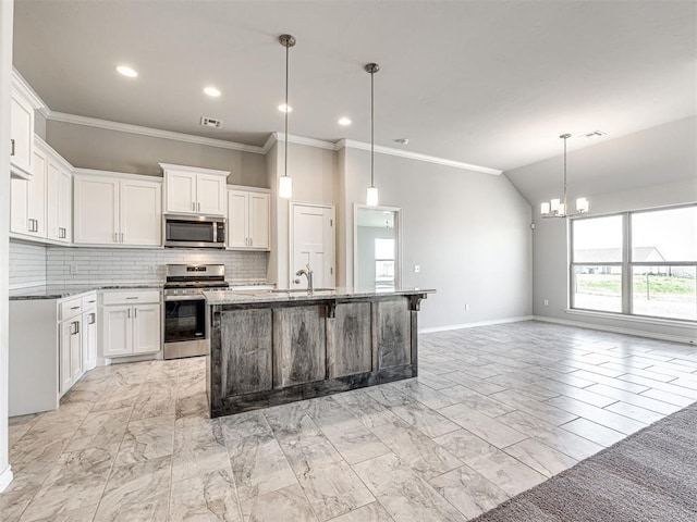 kitchen with white cabinets, decorative light fixtures, a center island with sink, and stainless steel appliances