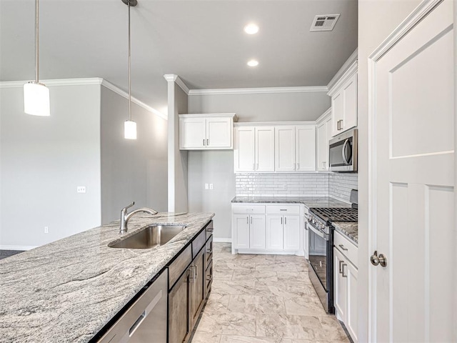 kitchen featuring white cabinets, appliances with stainless steel finishes, light stone counters, and sink