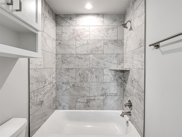 bathroom featuring tiled shower / bath combo and toilet