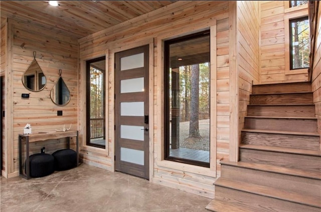 doorway featuring wood ceiling, wooden walls, and concrete flooring