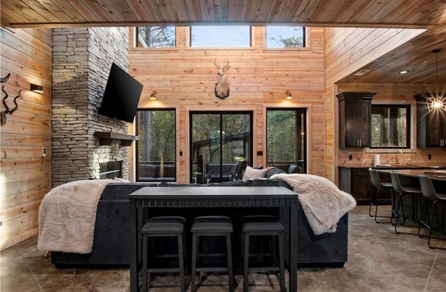 interior space with wood walls, a kitchen bar, dark brown cabinetry, and wood ceiling