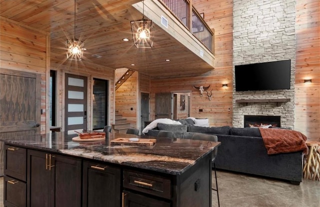 kitchen with a breakfast bar, dark stone counters, wooden walls, and wood ceiling