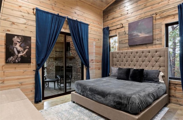 bedroom with access to exterior, high vaulted ceiling, and wood walls