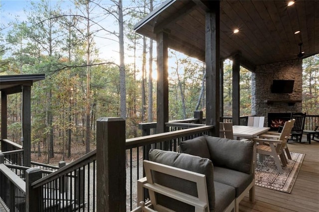 wooden terrace with an outdoor stone fireplace