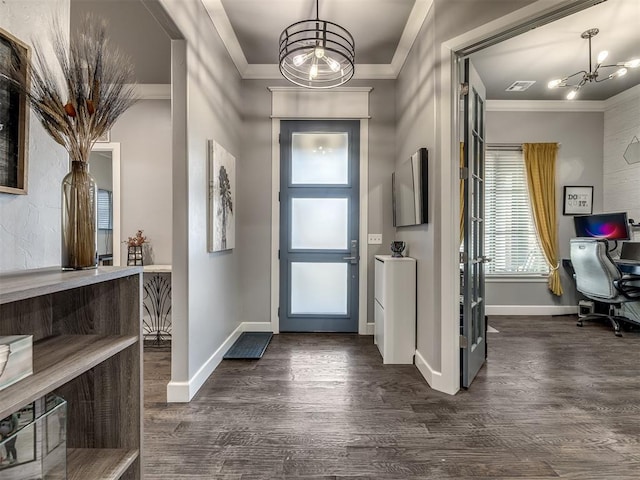 entrance foyer featuring dark hardwood / wood-style flooring, crown molding, and an inviting chandelier