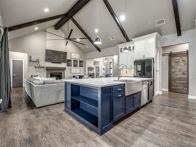 kitchen featuring dark wood-type flooring, blue cabinets, sink, a barn door, and white cabinetry