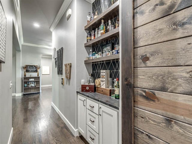 bar featuring dark hardwood / wood-style floors, white cabinetry, and ornamental molding