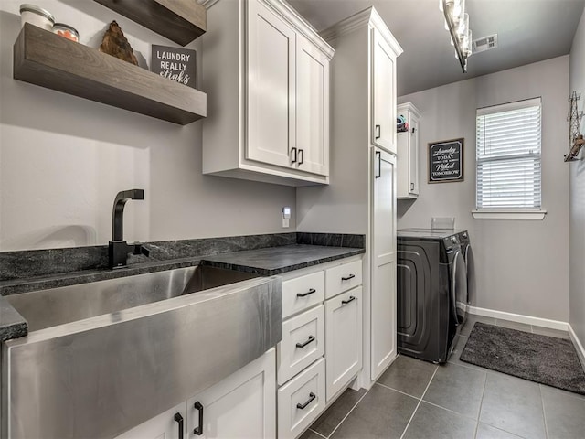 kitchen featuring sink, white cabinets, dark tile patterned flooring, and independent washer and dryer