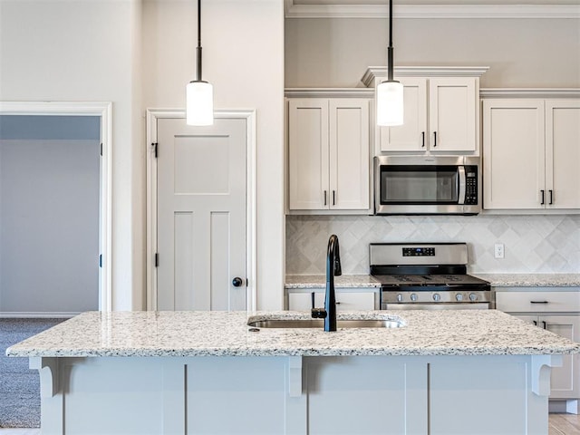 kitchen with sink, appliances with stainless steel finishes, decorative light fixtures, light stone counters, and white cabinetry