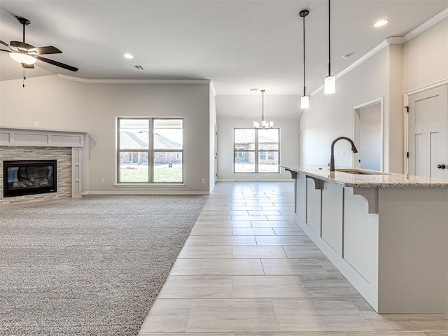 kitchen featuring light carpet, pendant lighting, a healthy amount of sunlight, and ceiling fan with notable chandelier