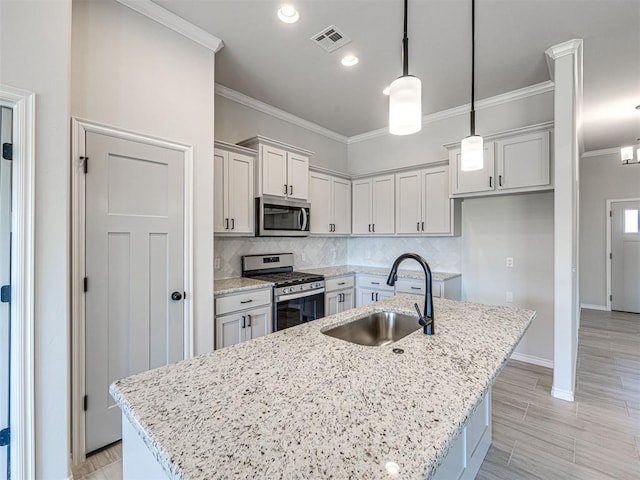 kitchen with a center island with sink, pendant lighting, sink, and stainless steel appliances