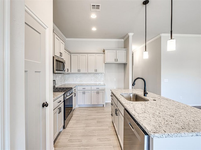 kitchen featuring a center island with sink, sink, hanging light fixtures, white cabinetry, and stainless steel appliances