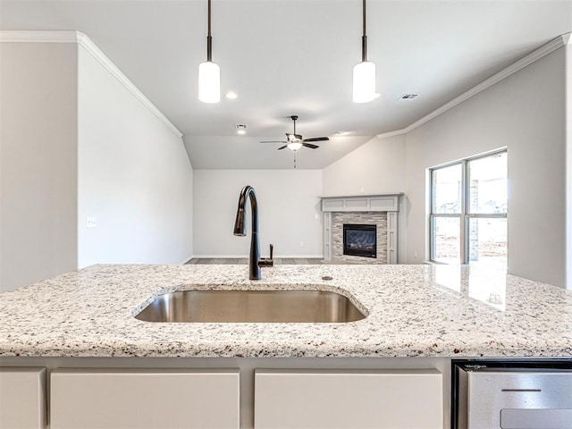 kitchen with light stone countertops, ceiling fan, sink, and pendant lighting