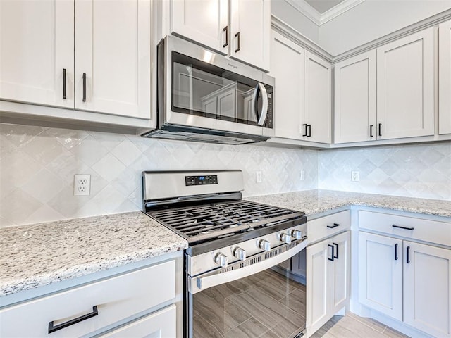 kitchen with backsplash, crown molding, light stone countertops, and stainless steel appliances