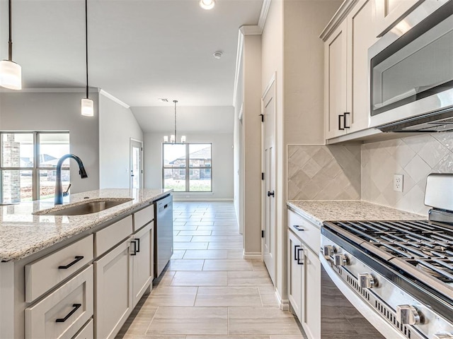 kitchen featuring decorative light fixtures, sink, light stone counters, and stainless steel appliances