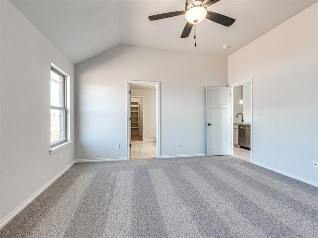 unfurnished bedroom featuring lofted ceiling, light carpet, ceiling fan, a spacious closet, and a closet