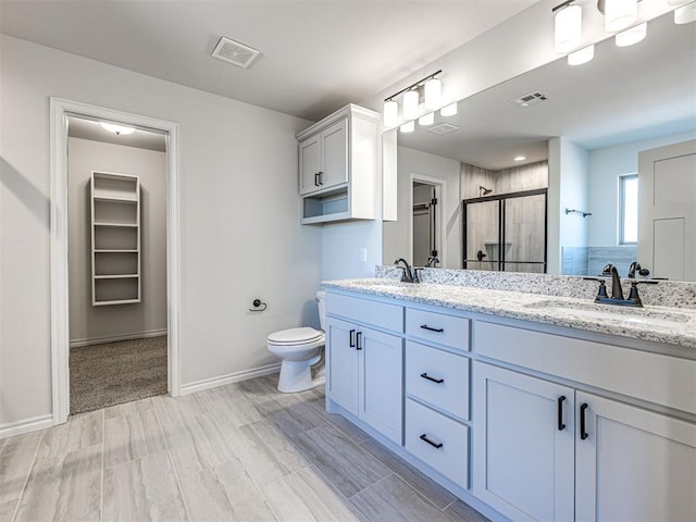 bathroom featuring vanity, toilet, and a shower with door