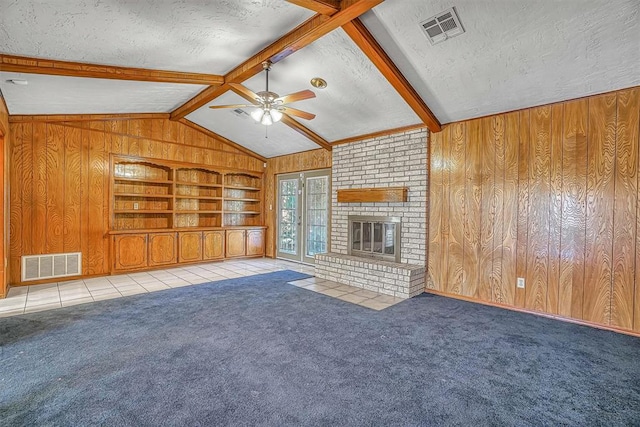 unfurnished living room with a brick fireplace, a textured ceiling, ceiling fan, wooden walls, and built in features