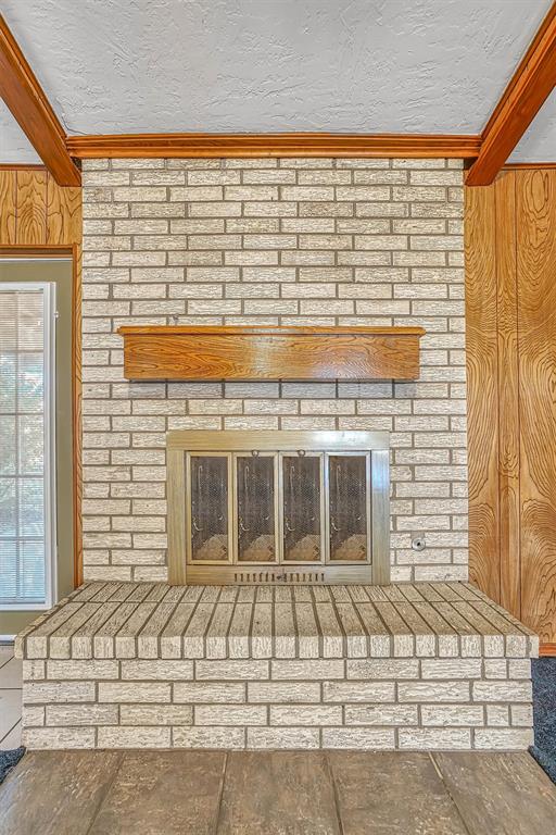 interior details with beam ceiling, ornamental molding, and a fireplace