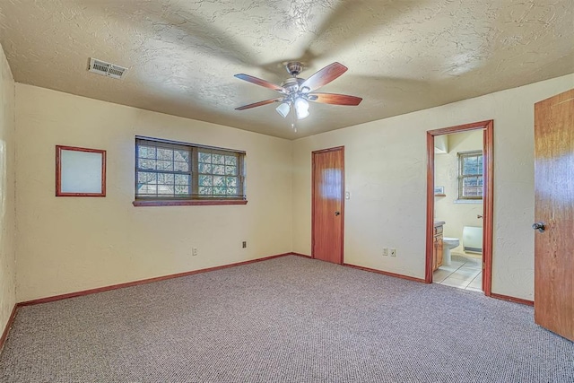 unfurnished bedroom featuring connected bathroom, ceiling fan, light colored carpet, and a textured ceiling