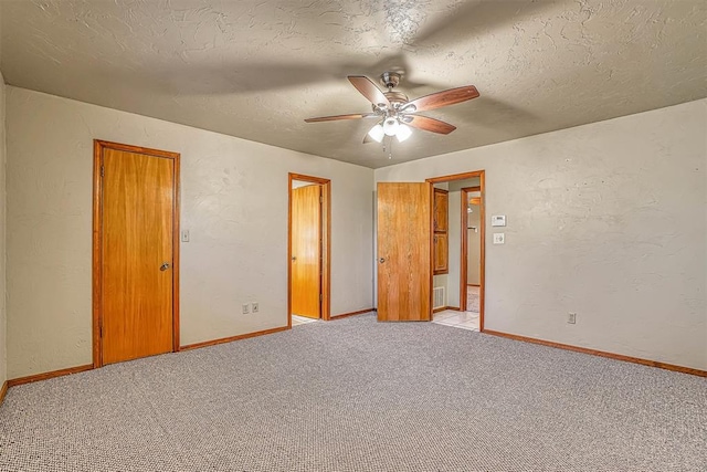 unfurnished bedroom with a textured ceiling, light colored carpet, and ceiling fan