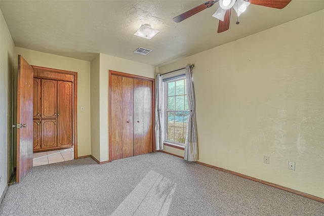 unfurnished bedroom featuring a textured ceiling, a closet, ceiling fan, and light colored carpet