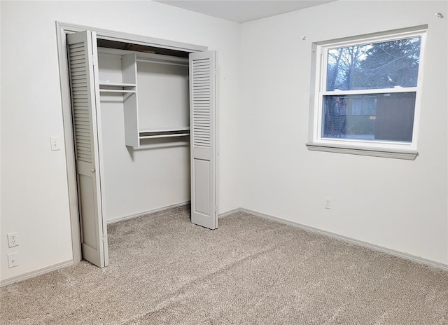 unfurnished bedroom featuring light carpet and a closet