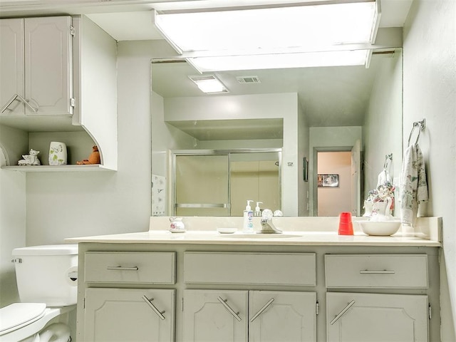 bathroom featuring toilet, a shower with door, and vanity