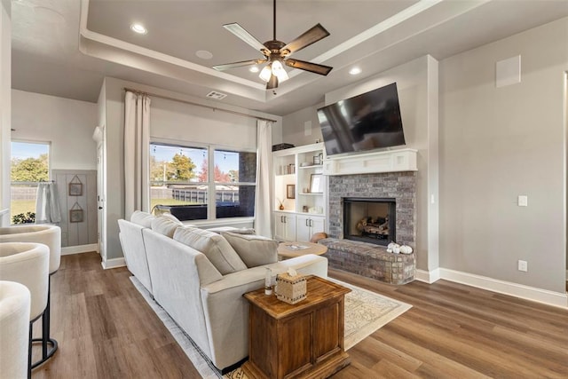 living room featuring wood-type flooring, a raised ceiling, and plenty of natural light