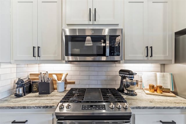 kitchen featuring tasteful backsplash, white cabinetry, appliances with stainless steel finishes, and light stone counters