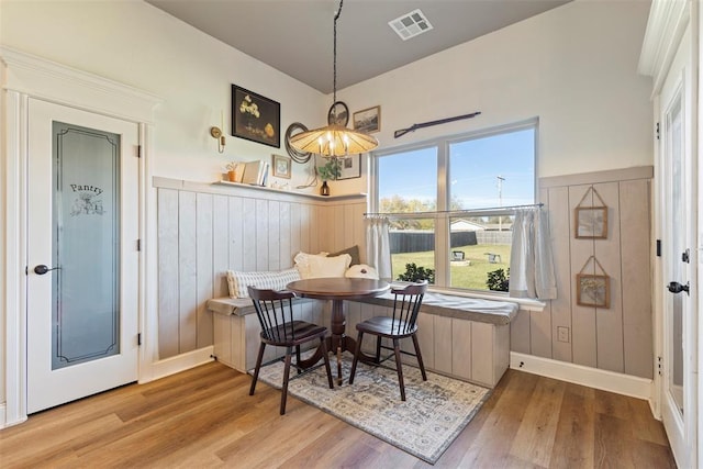 dining space with breakfast area, wood walls, and light wood-type flooring