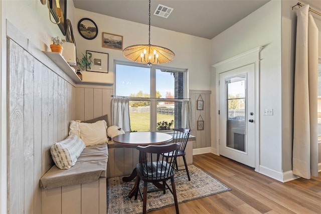 dining space featuring plenty of natural light, wooden walls, a notable chandelier, and light hardwood / wood-style floors