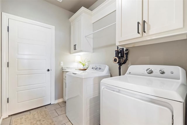 washroom with cabinets, light tile patterned floors, and washing machine and clothes dryer