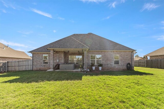 back of property with a lawn and a hot tub